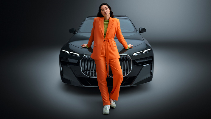 woman in an orange suit standing in front of a black car